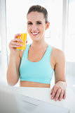Smiling woman in sportswear holding orange juice