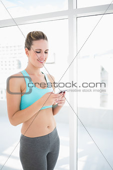 Smiling woman in sportswear using phone