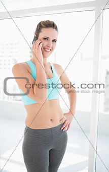 Smiling fit woman talking on the phone posing