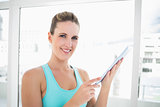 Cheerful woman in sportswear holding tablet