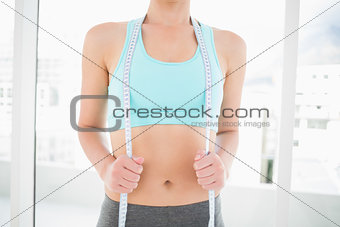 Woman wearing sportswear holding measuring tape