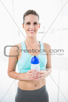 Smiling woman wearing sportswear holding flask