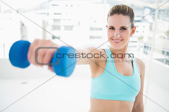 Portait of smiling woman exercising with dumbbell