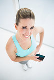 Smiling woman in sportswear using mobile phone