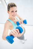 Fit smiling woman exercising with dumbbells