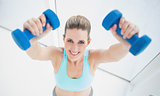 Cheerful blonde woman exercising with dumbbells