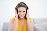 Happy woman with headphones sitting on sofa