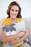 Happy woman sitting on sofa holding pillow