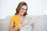 Peaceful woman wearing glasses reading newspaper