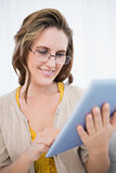 Smiling woman with glasses looking at tablet screen