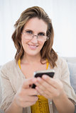 Smiling woman with glasses holding phone