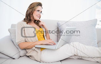 Thoughtful cute woman using laptop
