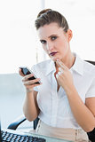 Businesswoman holding phone looking at camera