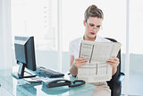 Serious businesswoman reading newspaper