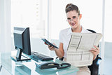 Smiling businesswoman holding newspaper and calculator
