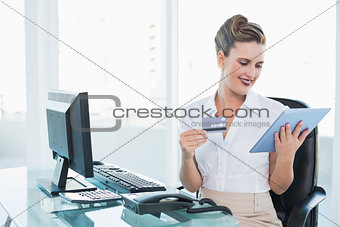 Smiling businesswoman holding tablet and credit card