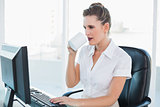 Attractive businesswoman drinking coffee and working on computer