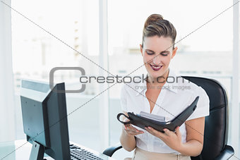 Smiling classy businesswoman looking at her datebook