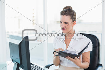 Businsswoman looking at computer screen while holding datebook