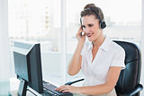 Cheerful call centre agent working on computer while having a call