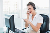 Smiling call centre agent pointing at something on computer screen