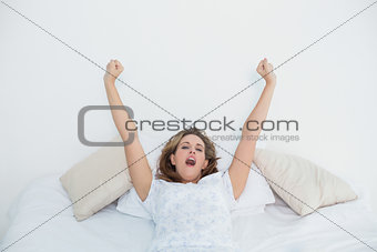 Pretty blonde woman stretching in bed and yawning