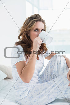 Attractive woman resting in bed drinking coffee