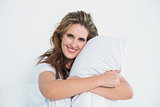 Smiling woman embracing pillow