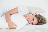 Smiling woman lying on bed embracing pillow
