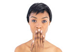 Serious black haired woman covering her mouth
