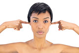 Serious black haired woman clogging her ears