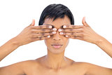 Serious black haired woman covering her eyes