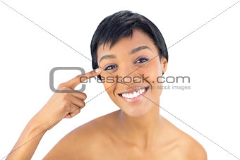 Smiling black haired woman posing with a finger on her temple