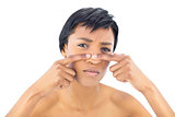 Frowning black haired woman popping a pimple