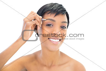 Content black haired woman plucking her eyebrows