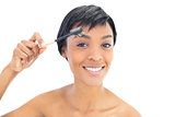 Happy black haired woman brushing her eyebrows
