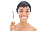 Happy black haired woman holding a brow brush