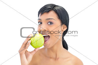 Delighted black haired woman eating an apple