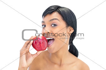 Pleased black haired woman eating an apple