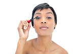 Concentrated black haired woman applying mascara