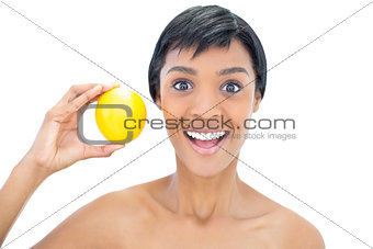 Happy black haired woman holding an orange