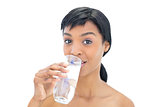 Amused black haired woman drinking a glass of water