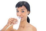 Delighted black haired woman drinking a glass of milk
