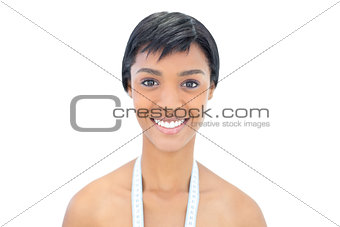 Happy black haired woman posing with a tape measure around the neck