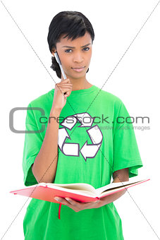 Pensive black haired model holding a notebook