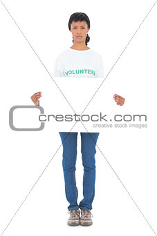 Unsmiling black haired volunteer holding a white panel in front of camera