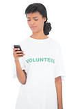Frowning black haired volunteer texting with her mobile phone