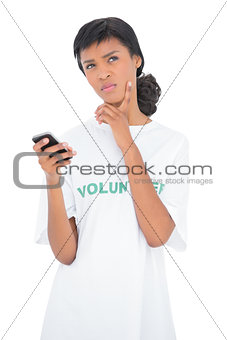 Thoughtful black haired volunteer holding a mobile phone