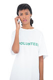 Disappointed black haired volunteer calling someone with her mobile phone