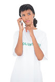 Wondering black haired volunteer calling someone with her mobile phone
